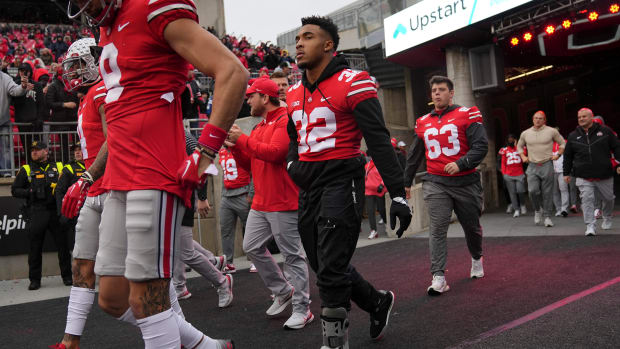 TreVeyon Henderson walks out of the tunnel in a walking boot.